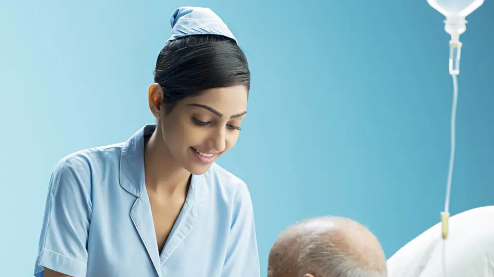 A nurse helping an older patient eat at his hospital bed