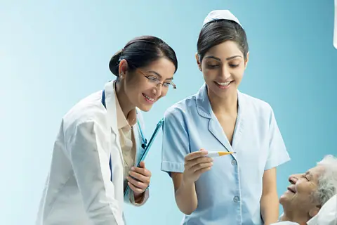 A doctor and a nurse smiling at a patient in a hospital bed
