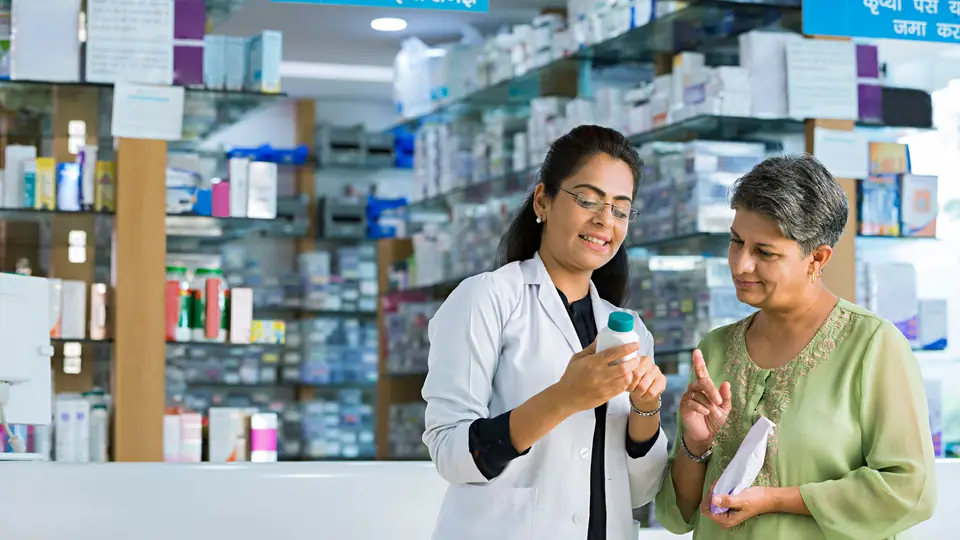 A pharmacist explaining a medicine bottle to a customer at the counter