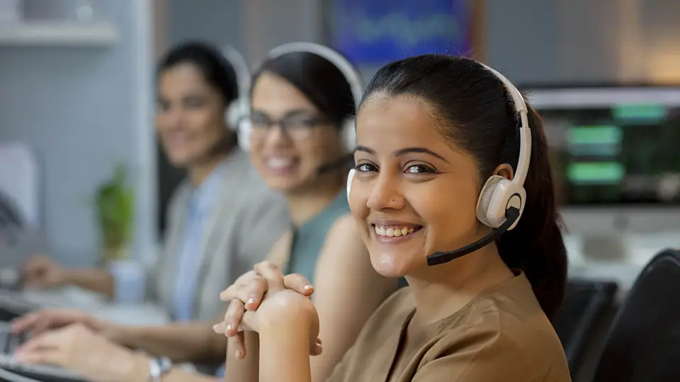 Three colleagues in headsets working at computers in a support office