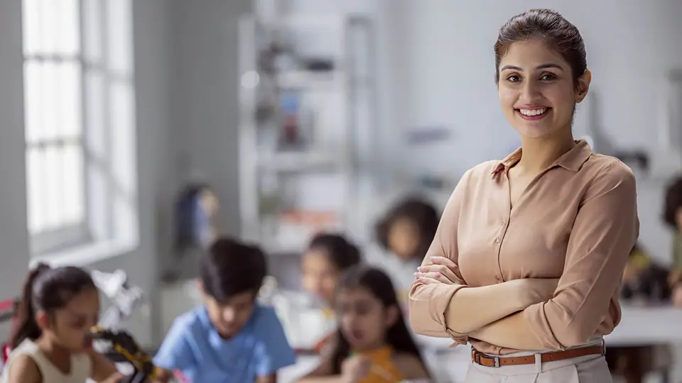 A teacher standing with her arms crossed in a classroom of working children